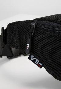 Borsa in rete nera FILA con chiusura a zip, etichetta con logo e tracolla regolabile con fibbia in plastica.