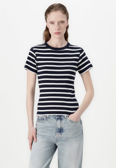 T-shirt rayé bleu marine et blanc avec une texture côtelée, des manches courtes et un col rond, associé à un jean taille haute bleu clair.
