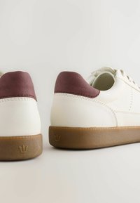 Hvide sneakers med en bordeaux hælkappe og sål af gummi. Glat læderoverdel med tonal syning og et krone-logo på hælen.