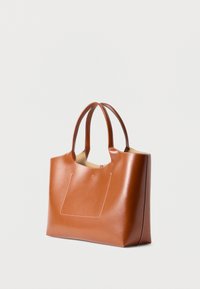 Καφέ δερμάτινη τσάντα ώμου με διπλές λαβές, εμφανή ραφές και λεπτομέρεια μπροστινής τσέπης, επάνω σε απλό λευκό φόντο.