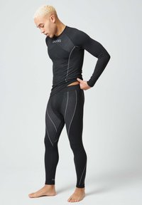 Zwart sportief longsleeve shirt en aansluitende leggings met witte accenten en geprofileerde panelen. Rekbare stof zorgt voor gemakkelijke beweging.