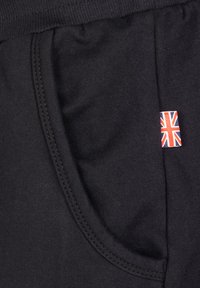 Črne bombažne trenirke s stranskimi žepi, ki imajo majhno oznako Union Jack. Gladka tekstura z našitimi šivi za trajnost.