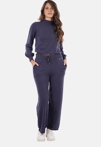 Tuta in cotone blu navy composto da un top a maniche lunghe con colletto alto e pantaloni larghi con cordino regolabile e tasche.