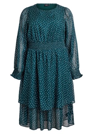 Petrol zaļa kleita ar garām caurspīdīgām piedurknēm, smockotu jostas daļu, slāņotu apakšu un punktiņu rakstu. Izgatavota no viegla, teksturēta auduma.