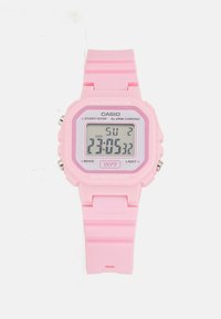 Montre numérique rose avec un boîtier carré, bracelet en plastique, fonction de résistance à l'eau et écran LCD affichant l'heure et le jour de la semaine.