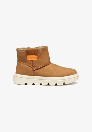 Botas de ante marrón hasta el tobillo con suela de goma blanca, que presentan un acento naranja en la parte trasera y costuras decorativas a lo largo del costado.