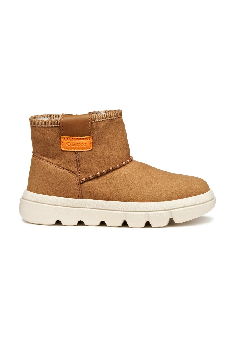 Botas de ante marrón hasta el tobillo con suela de goma blanca, que presentan un acento naranja en la parte trasera y costuras decorativas a lo largo del costado.