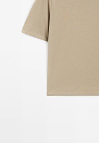 Beige Baumwoll-T-Shirt mit kurzen Ärmeln, rundem Ausschnitt und sauberen Nähten. Glatte Textur, entspannte Passform, keine sichtbaren Muster oder Akzente.