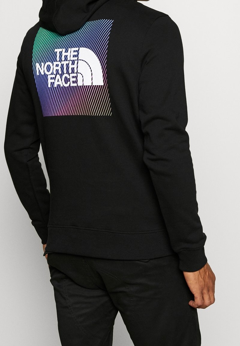Czarna bluza z kapturem z logo "The North Face" z gradientowym wzorem w kolorach niebieskim, zielonym i fioletowym. Wykonana z miękkiej, teksturowanej tkaniny.
