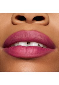 Rouge à lèvres mat avec un dégradé de rose profond à rose clair sur des lèvres pleines, mettant en valeur une texture lisse et une application uniforme, avec des dents blanches visibles.