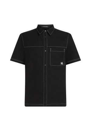 Camisa de manga corta de algodón negro, con costuras en contraste blancas, un bolsillo en el pecho y un acento de logo en el bolsillo.