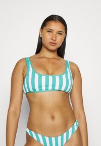 Top de biquíni em azul-turquesa e branco com acabamento texturizado, alças finas e decote em scoop. Acompanhado por um fundo correspondente.