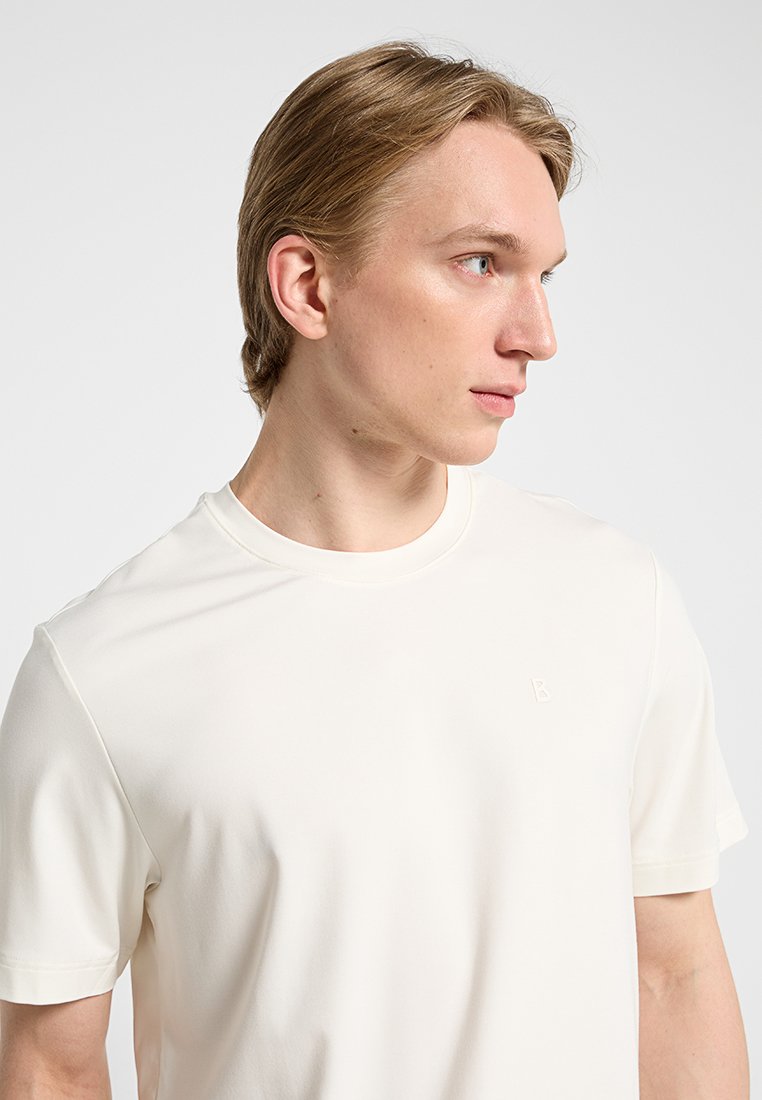 Helles Cremefarbenes T-Shirt mit kurzen Ärmeln aus glattem Stoff, versehen mit einem minimalistischen,prägten Logo auf der Brust. Gerader Schnitt.