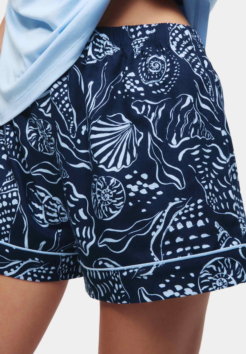 Marinblå shorts med ett vitt skal- och sjögrästryck, med resårmidja och kontrasterande detaljer i fållen.