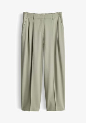 Pantalon taille haute beige clair avec plis, poches latérales, passants pour ceinture et fermeture éclair devant.