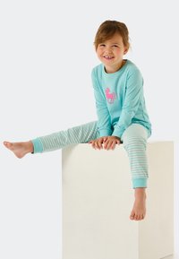 Helles blaues Schlafanzug-Set mit Einhorn-Motiv auf dem Oberteil und gestreiften, hellblauen und weißen Hosen. Weicher Stoff, lässige Passform und gerippte Bündchen.