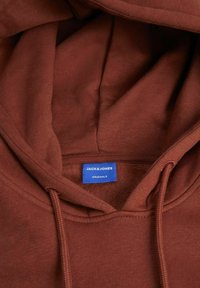 Felpa con cappuccio marrone realizzata in morbido tessuto, con un'etichetta blu che presenta "JACK & JONES" e "ORIGINALS", caratterizzata da un design semplice.