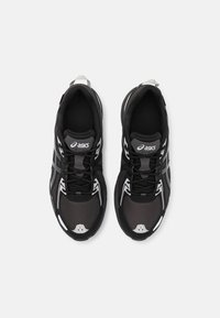 Schwarze Laufschuhe mit einem Obermaterial aus Mesh, grauen Akzenten und einer gepolsterten Sohle. Sie verfügen über kontrastierende weiße Details und eine traditionelle Schnürung.