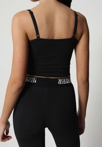 Top a canotta nera aderente con spalline regolabili, abbinato a leggings neri a vita alta con un elastico in vita a contrasto.