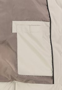 Beige stof met een gladde textuur heeft een contrasterende donkere rand en een zijzak in een lichtere tint, wat een minimalistisch ontwerp laat zien.