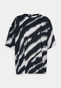 Camiseta de tie-dye en blanco y negro, de manga corta, cuello redondo, corte holgado, con textura suave y rayas irregulares a lo largo de la tela.