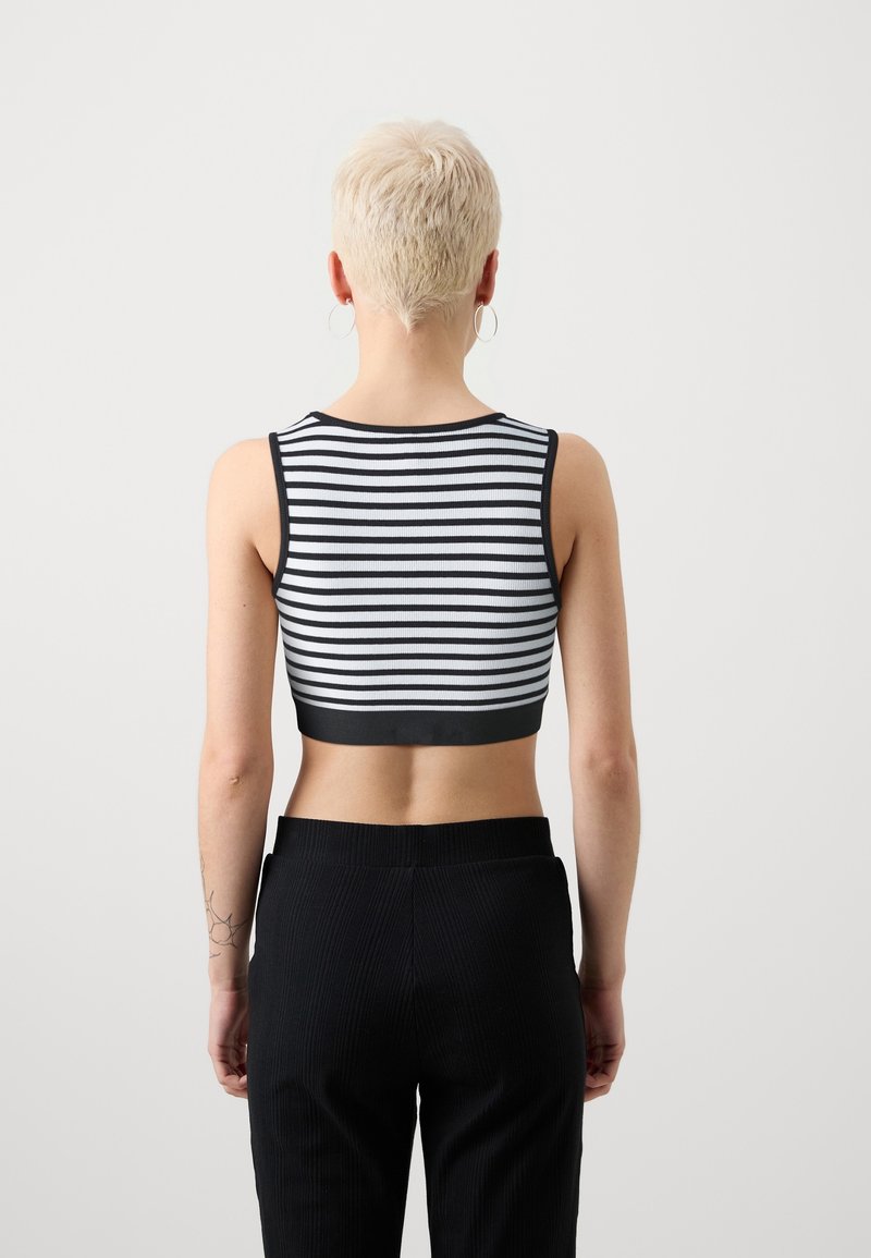Black and white striped crop top with a fitted design, showing exposed midriff, featuring ribbed texture and a solid black band at the hem.