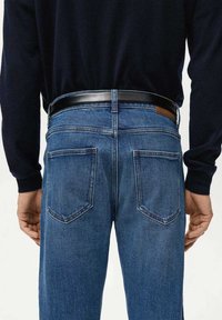 Pantalones vaqueros de mezclilla azul oscuro con corte recto, que cuentan con dos bolsillos traseros y un cinturón negro en la cintura, mostrando una textura suave.