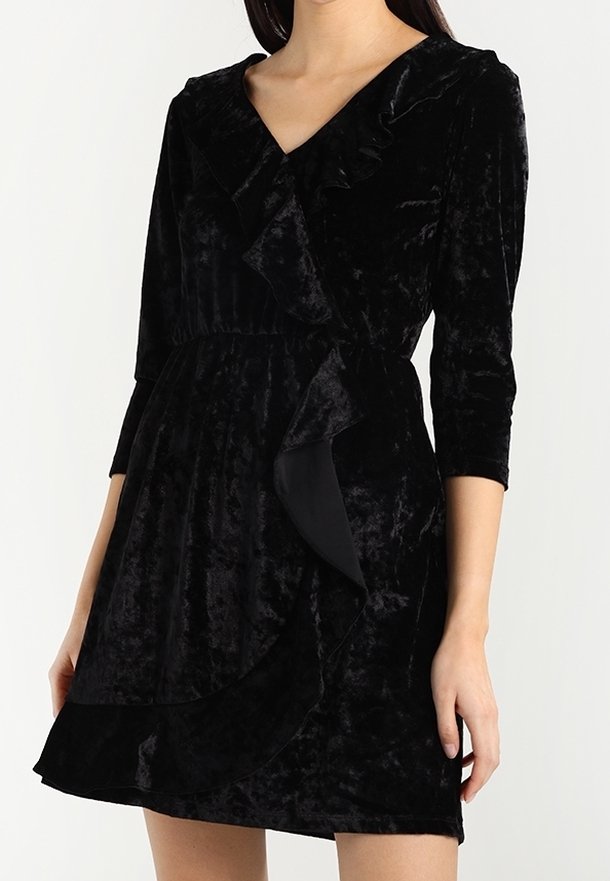 Robe noire en velours avec un col en V, des manches trois-quarts et un détail froncé à l'avant. Texture lisse avec une taille ajustée et un ourlet évasé.