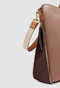 Bolso bandolera marrón y beige con exterior de cuero, acabado texturizado, herrajes dorados y una correa beige a contraste. Detalle de cremallera visible.