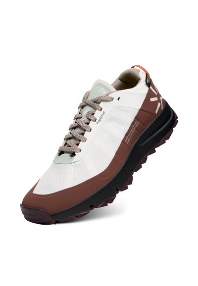 Chaussures de trail de course blanches et marron avec des lacets beige, semelle noire, grip texturé et logo à l'arrière, inclinées vers la droite sur fond blanc.