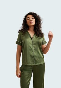 Completo pigiama in raso verde composto da una maglietta a maniche corte con piping bianco e dettagli in pizzo sui polsini, abbinato a pantaloni coordinati.