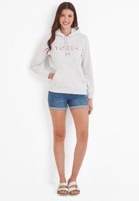 Light gray hoodie with pink text, drawstring hood, and front pocket, paired with denim shorts and silver slides. Plain background.