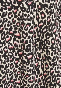 Leopardmönstrat tyg med svarta och beige fläckar, framhävt av små rosa accentfärger och en subtil texturerad väv.