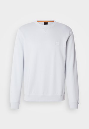 White sweatshirt with long sleeves, crew neckline, and subtle logo patch. Smooth texture and ribbed cuffs and hem for a fitted look.