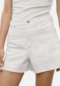 Shorts en denim blanc à taille haute, avec un ourlet effiloché, des poches avant, une fermeture à bouton argenté et des détails de couture subtiles. Tissu léger.