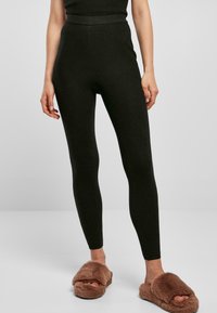 Mørkegrønne ribbede leggings med høy midje og en tettsittende design. Kombinert med brune fluffy kosesandaler for et koselig utseende.