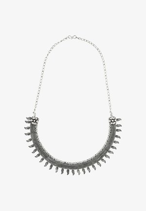 Metallisk halskæde med et buet design; har indviklede detaljer og små vedhæng. Sølvfarvet med en struktureret finish og kædelås.