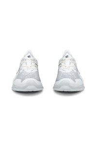 Scarpe da ginnastica bianche con una tomaia in rete texturizzata e accenti grigio chiaro, una punta arrotondata e una suola bianca flessibile.