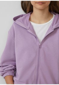 Hellblaues Zip-Hoodie mit weicher Textur, ausgestattet mit einer Kordelzugkapuze, gerippten Bündchen und einem weißen T-Shirt darunter.