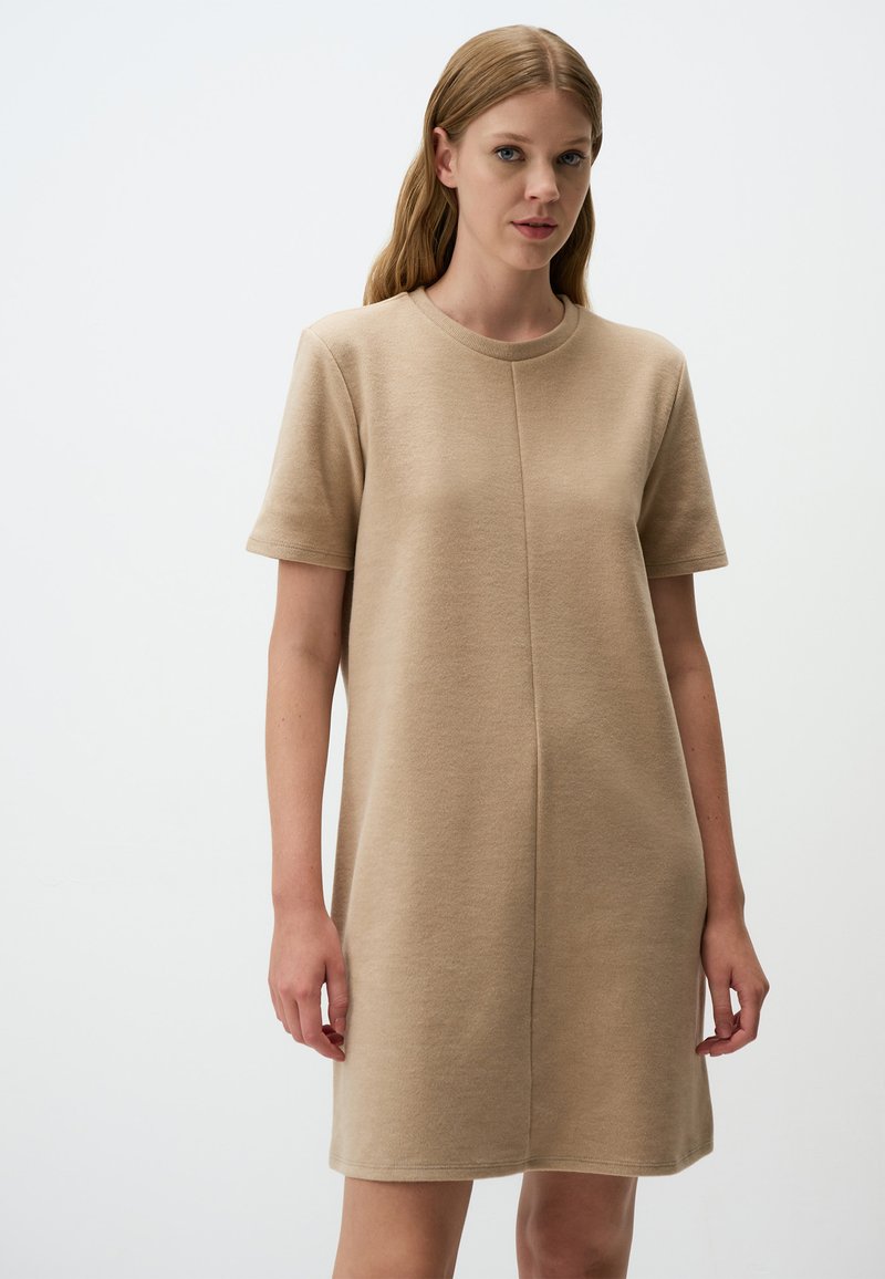 Beige Kurzarmkleid aus einem weichen Strickstoff. Verfügt über einen runden Halsausschnitt und einen geraden Schnitt mit einer Mittelnahtdetail.