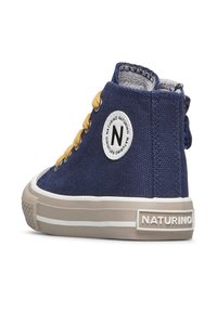 Námořnické plátěné vysoké boty s žlutými tkaničkami a bílou logo nášivkou. Mají gumovou podrážku a kontrastní béžovou gumovou mezipodrážku.