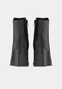 Μαύρες μποτες ακριβώς πάνω από τον αστράγαλο με ματ φινίρισμα. Χοντροί, υφασμάτινοι γοφοί και πλαϊκά φερμουάρ. Λείο σχέδιο με αεροδυναμικό σχήμα.