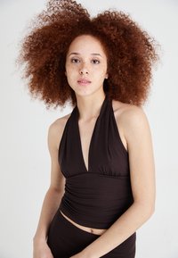 Top marou de culoare maro, cu guler halter și decolteu adânc în formă de V, având detalii căptușite la talie, fabricat dintr-un material moale și elastic, asortat cu o piesă de jos corespunzătoare.