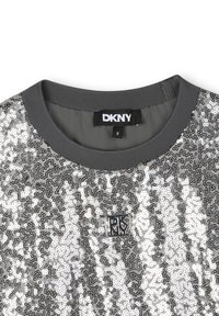 Zilveren pailletten top met een grijze rib gebreide ronde hals. Kenmerkt DKNY branding label en een textuurpatroon van pailletten over de stof.