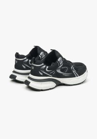 Zwarte sportschoenen met een bovenwerk van mesh, voorzien van zilveren accenten en een dikke witte zool. Textuurontwerp voor grip en ondersteuning.