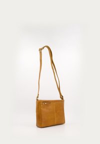 Ochre leather crossbody bag with a flat, rectangular shape, adjustable strap, and a front zipper pocket. Smooth texture and minimal design.