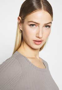 Gray ribbed top with a rounded neckline. Fabric is textured, fitting closely to the body, with a smooth, seamless appearance around the collar.