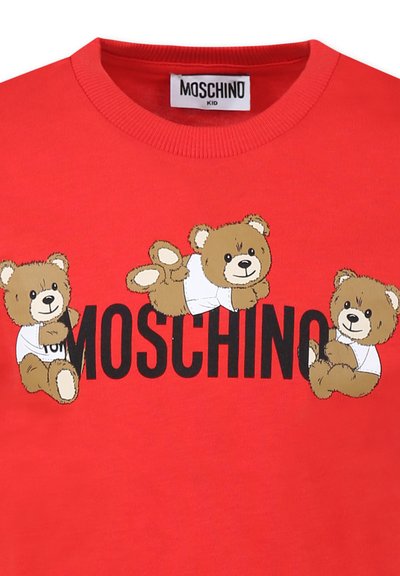 T-shirt en coton rouge avec trois oursons en bande dessinée portant des chemises blanches, et un texte noir en gras "MOSCHINO" en dessous. Encolure ronde.