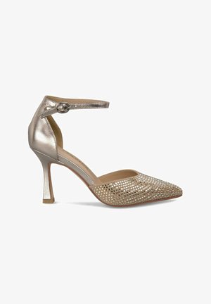 Chaussure à talon haut en or métallisé avec bride de cheville, bout pointu et tige en maille ornée de petites découpes. Talon de 3 pouces.