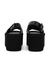 Sandali neri con plateau caratterizzati da una texture simile al suede, tacco largo, cinturino regolabile e semplici fibbie per una vestibilità sicura.